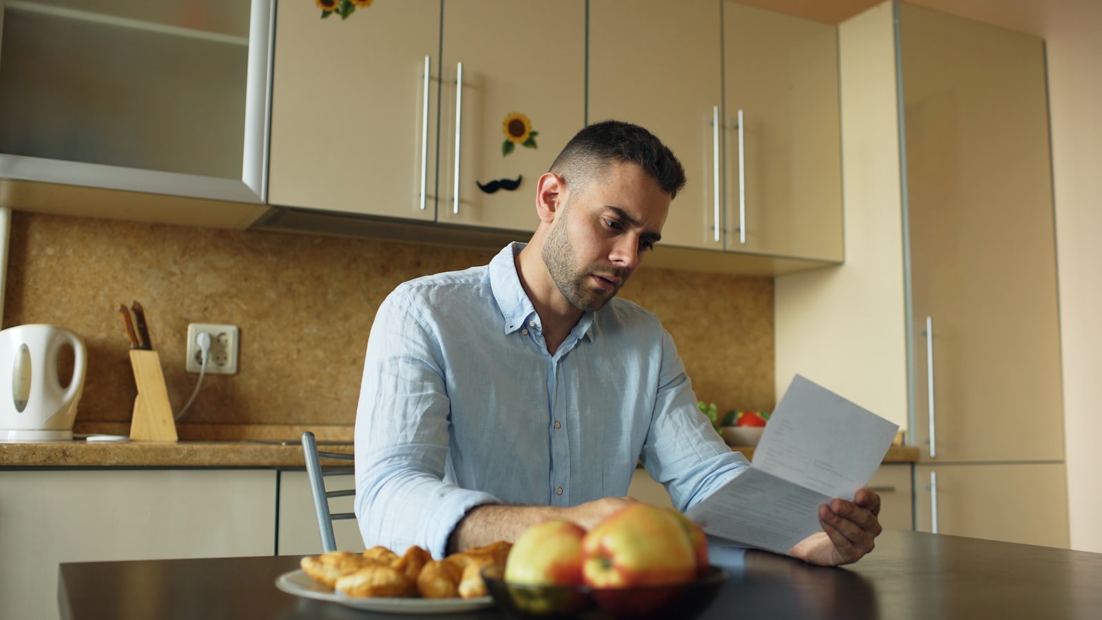 A person reading a document at a sunlit kitchen table